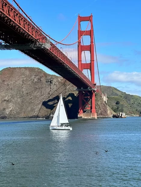 Sailboat sailing under the golden gate bridge on a sunny day in San Francisco - a boat trip is a must-do during 4-days in Northern California with kids