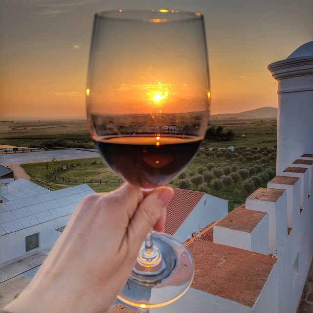 Glass of red wine with a view of sunset through the glass in Alentejo, Portugal
