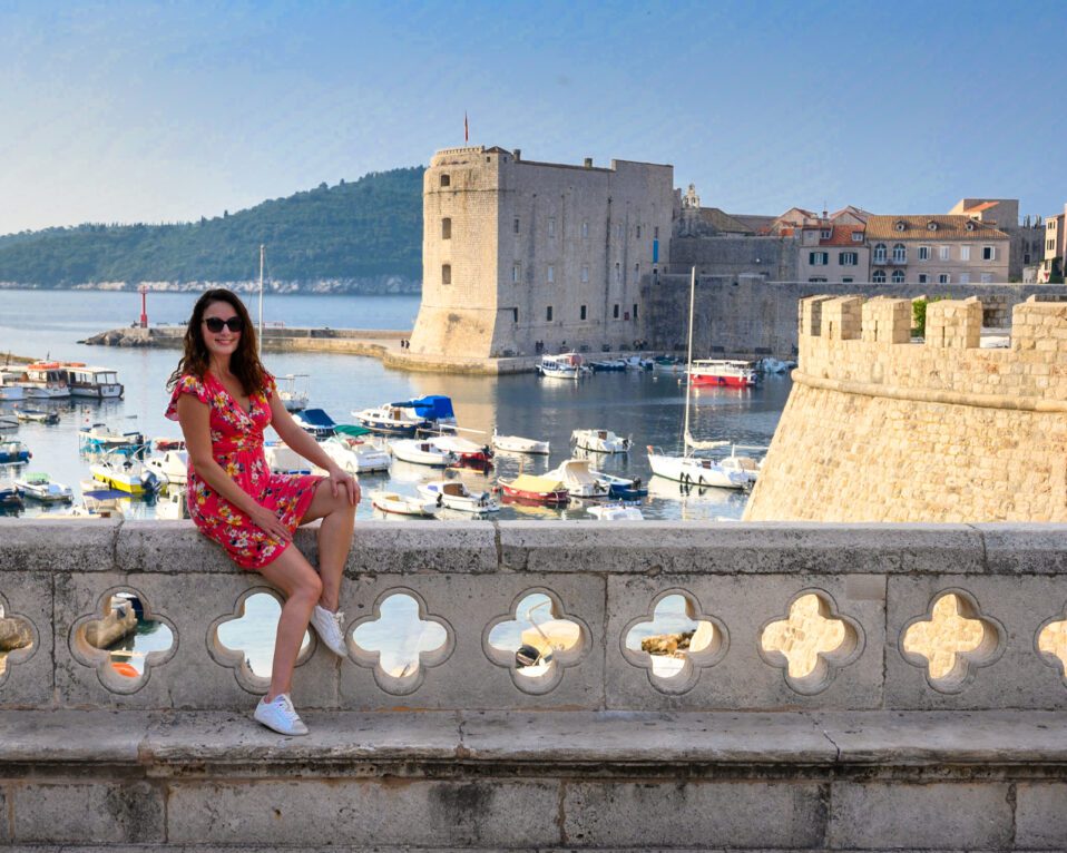Dubrovnik is a must visit if you have 2 weeks in Croatia | Woman from Adventurous Tastes posing in front of Dubrovnik scenic view on her two weeks in Croatia vacation