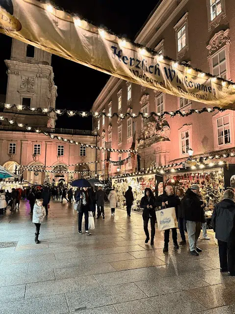 Salzburg's Austrian Christmas Market at night with festive golden banners and twinkling lights