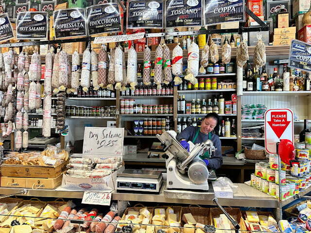 Woman slicing meat at Molinari's deli, a perfect family-friendly dining option in San Francisco, when spending 4 days in Northern California with kids