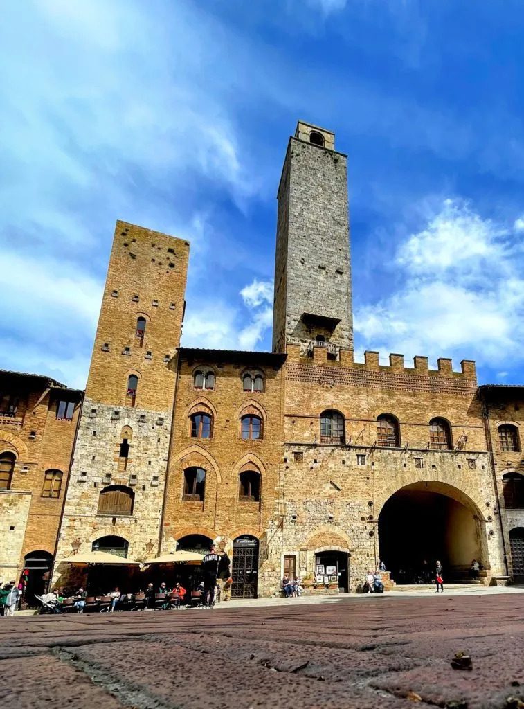 San Gimignano is a must-see destination to see when in Tuscany with kids. It's stone towers loom under a blue sky