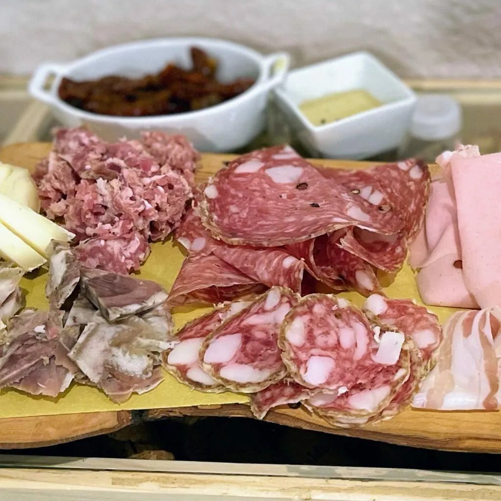 Great food is a highlight of visiting Tuscany with Kids. Close up of a pork charcuterie spread in San Gimignano in Tuscany