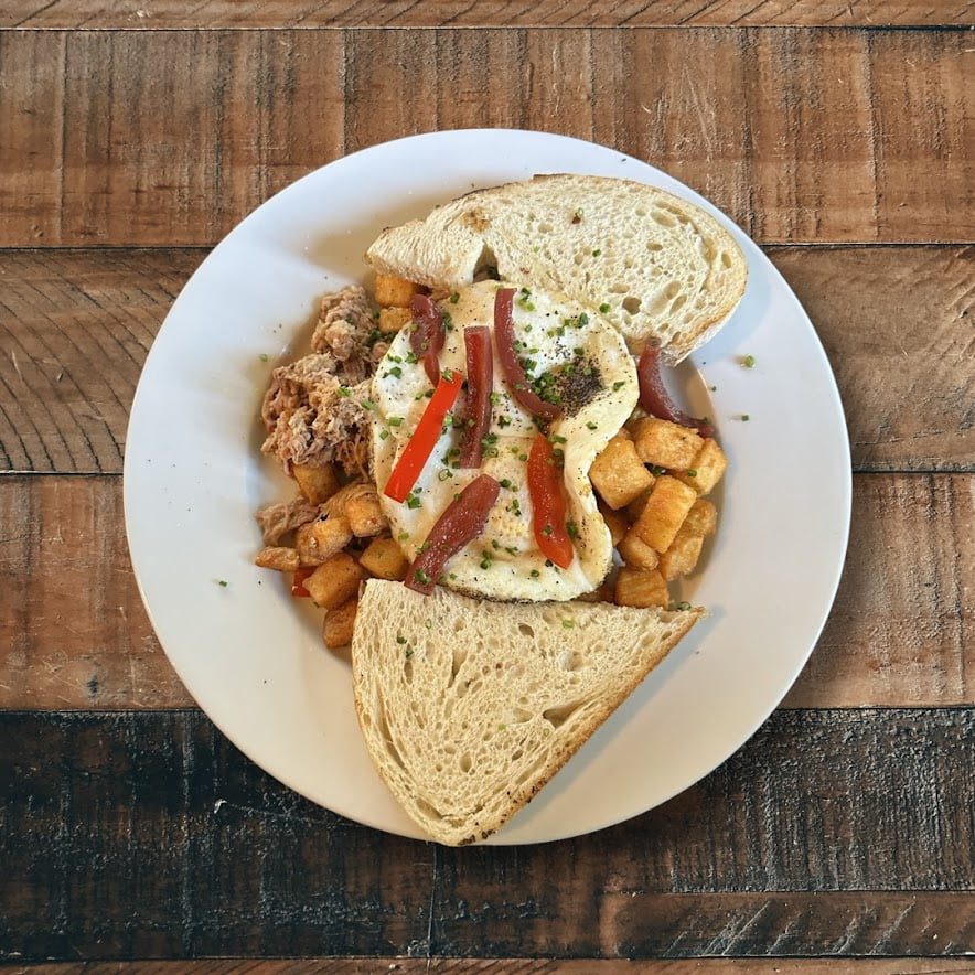 Plate of corned beef hash and eggs and toast on a wooden table at the Conover Club in the Catskills