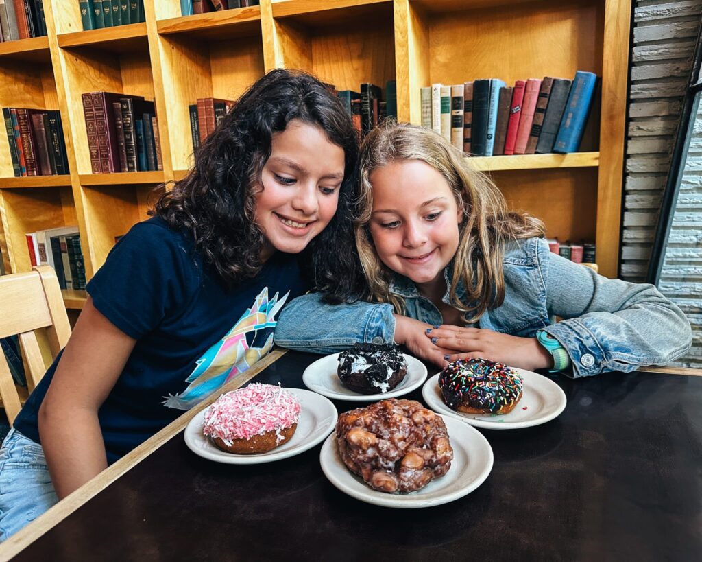 Two young girls looking happily at plates of doughnuts in Seattle