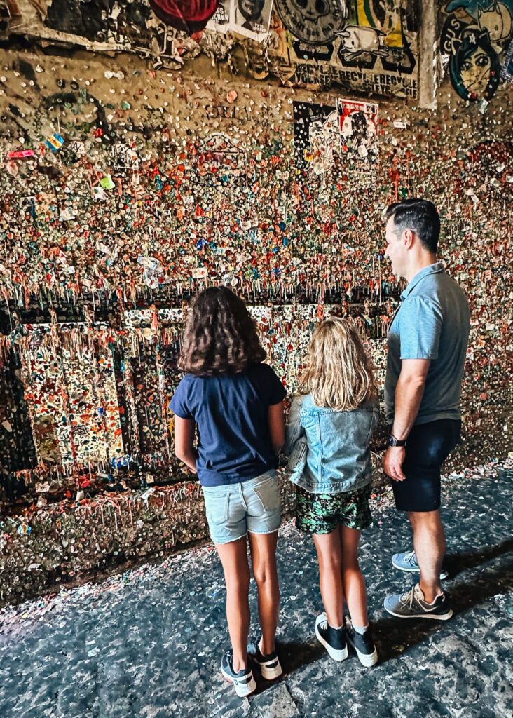 Man and two daughters looking at gum wall at Pike's Market in Seattle