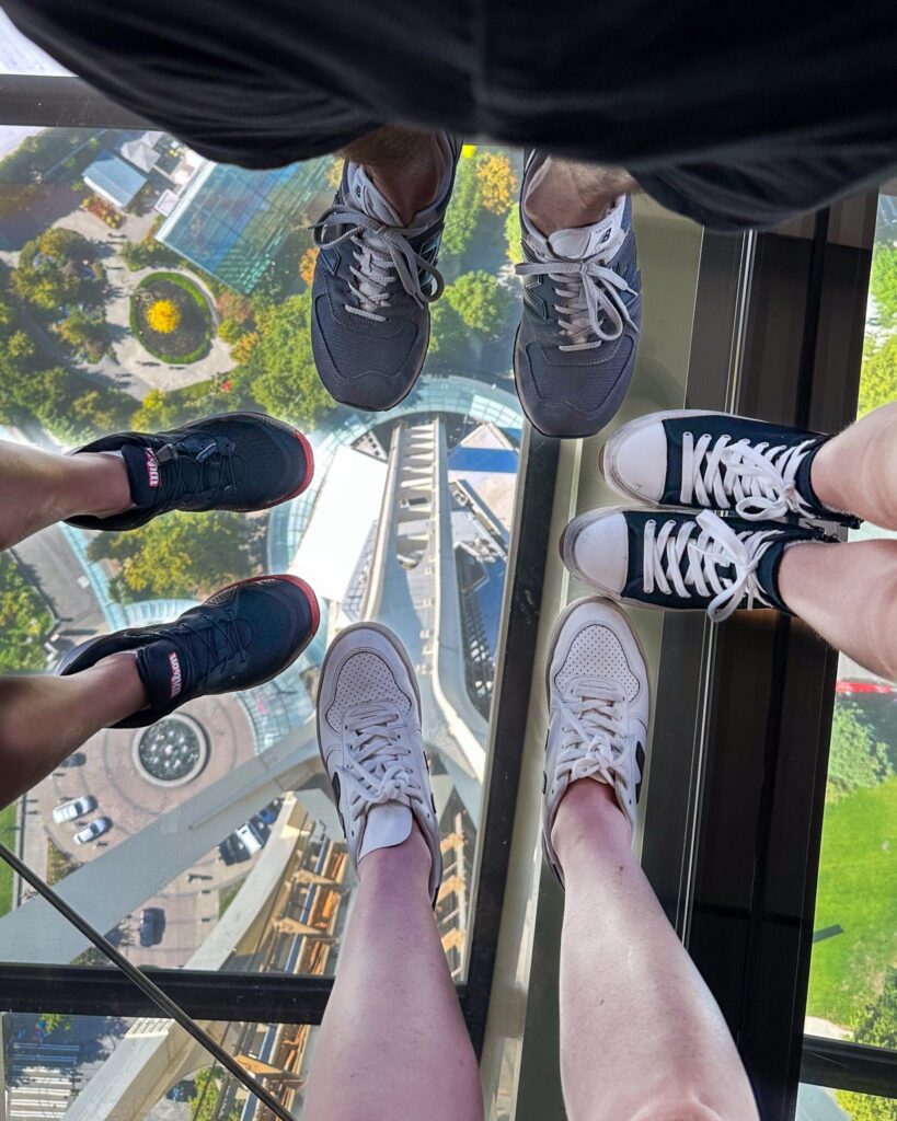 Four sets of feet looking through the glass floor at Seattle's Space Needle