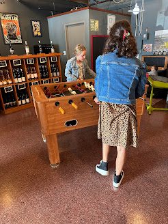 Two girls from Adventurous Tastes playing foosball at Two Vintners in Woodinville near Seattle