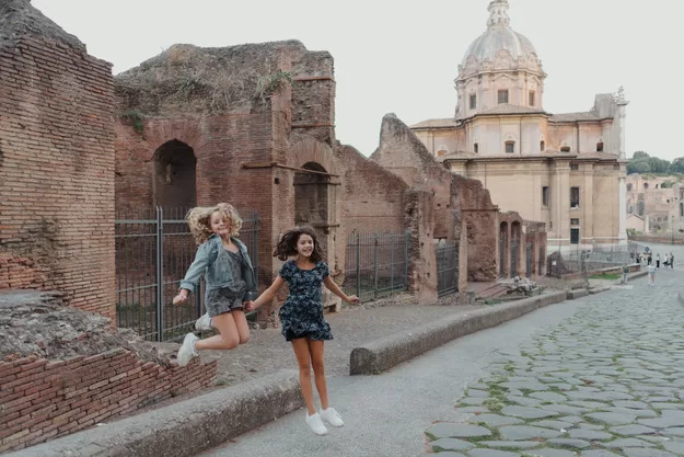 The key to traveling in Rome with kids - letting them play. Here two girls burn some energy by jumping near ruins.
