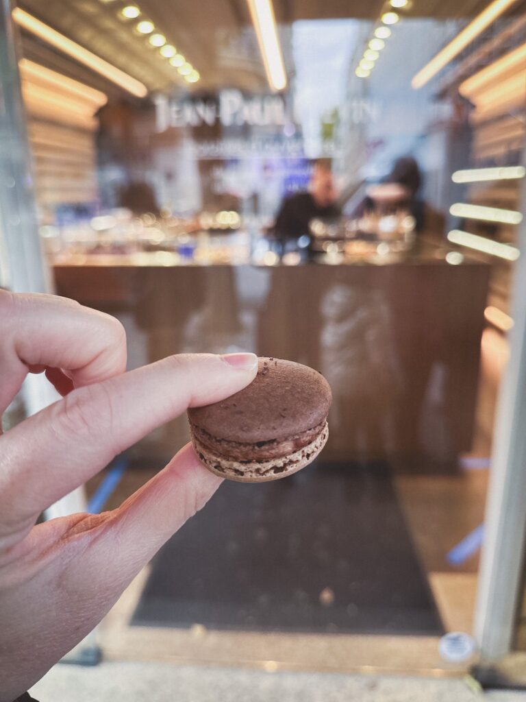 Close up of a chocolate macaron held in a woman's hand in Paris