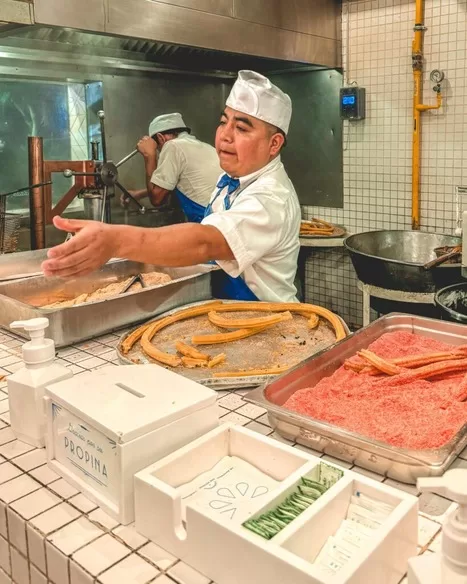 Go on a taco tour when you visit Mexico City with kids. A man serves churros at El Moro one of the best things to do in Mexico City