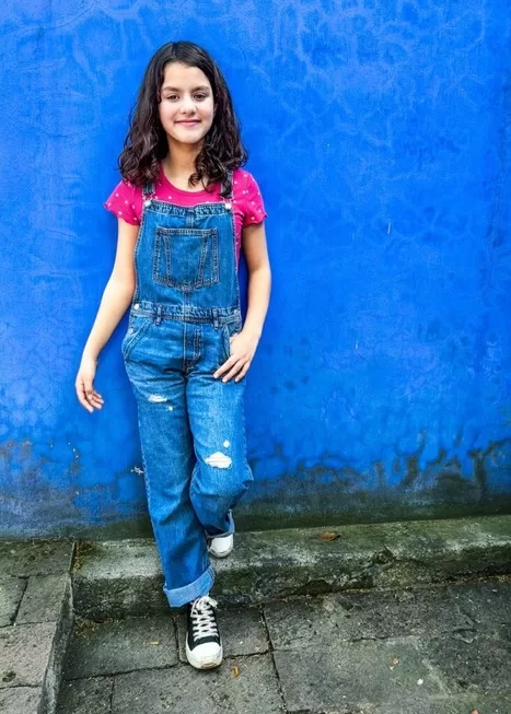 Casa Azul is a must when visiting Mexico City with Kids | Girl in overalls posed in front of blue wall at Casa Azul in Mexico City