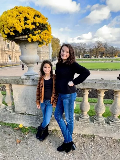 Dark haired woman and daughter posing on a fall visit to the Jardin du Luxembourg, one of the best places to visit in Paris with Kids