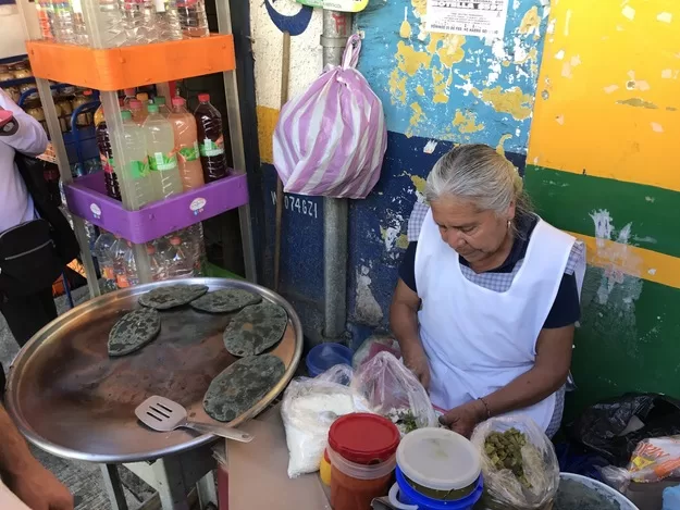 Old woman cooking street food outside a Mexico City market | a market tour is one of the best things to do wheh you visit Mexico City wtih kids