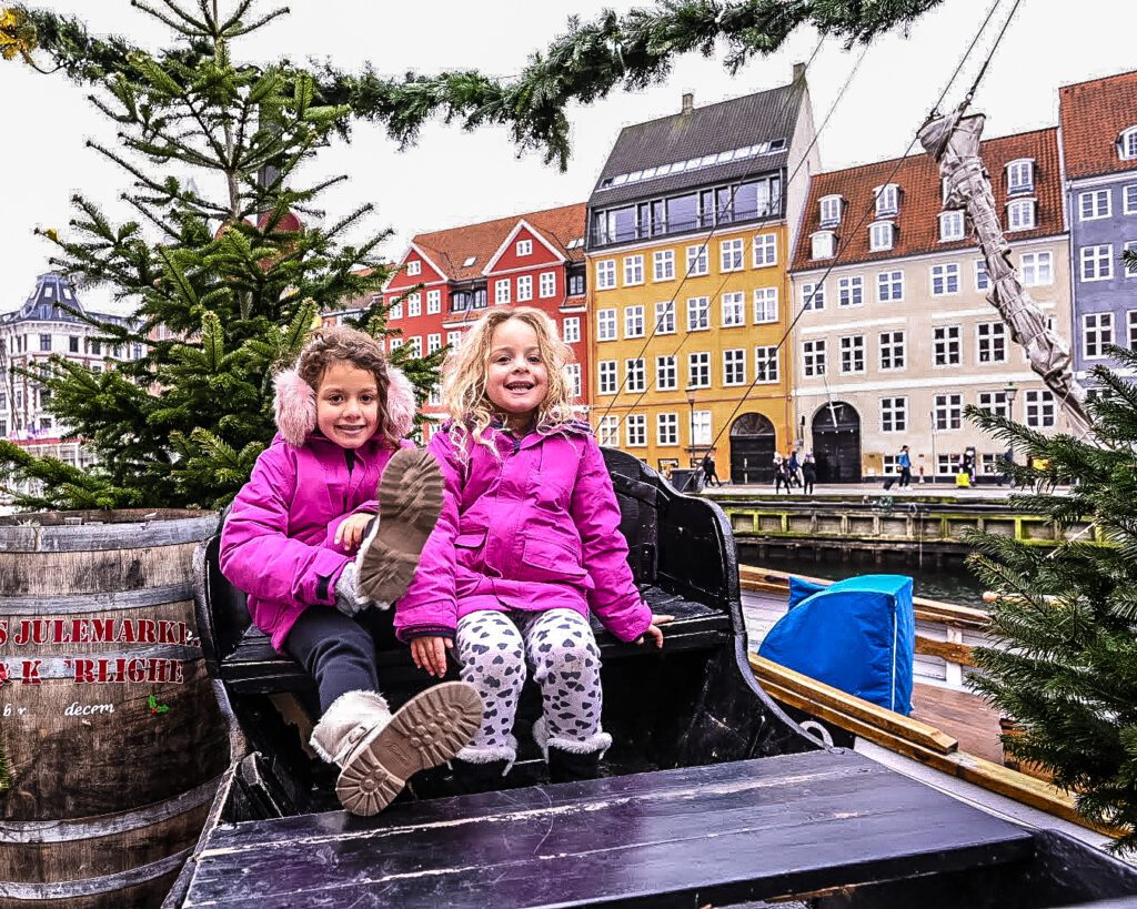 Little girls in winter clothes seated in a sleigh at Nyhaven Christmas market in Copenhagen