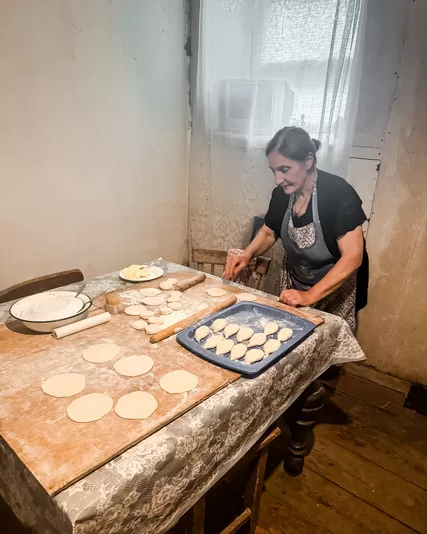 Old woman making Georgian khachapuri at a table