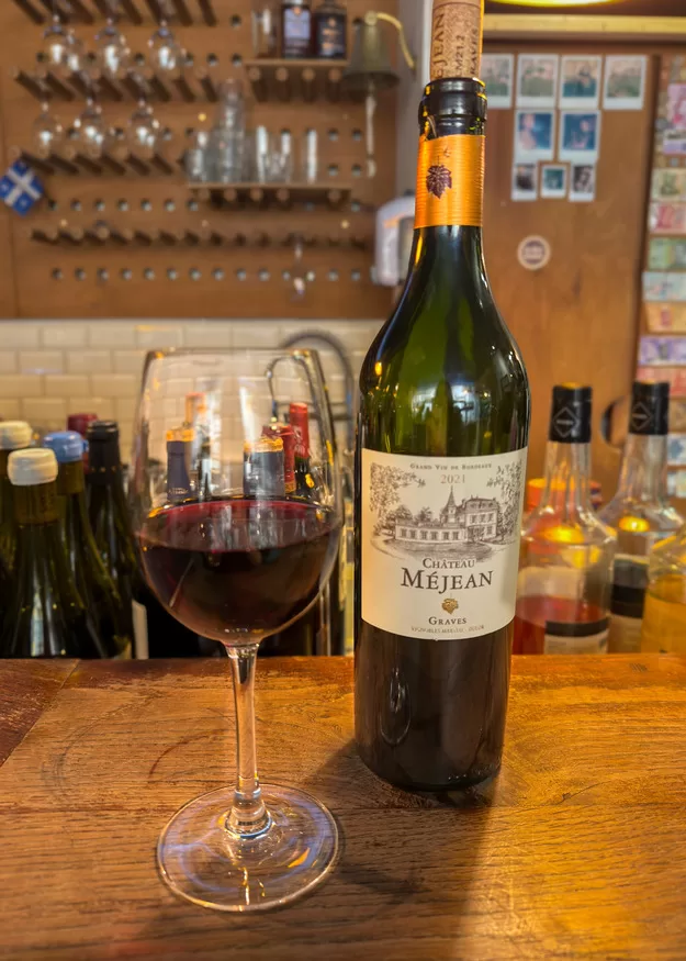 A bottlle of red wine and a glass of wine on the bar at Les Trois Pinadiers in Bordeaux