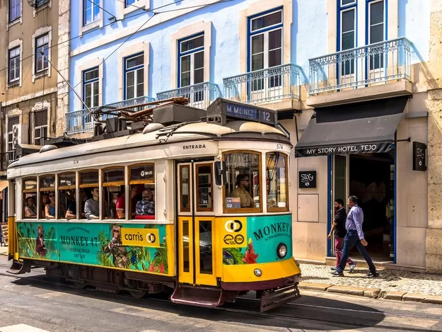 Yellow and green street car going down the street in Lisbon, Portugal