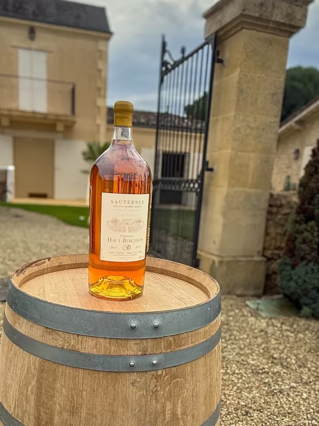 A golden bottle of sauternes wine sitting on a barrel in Bordeaux