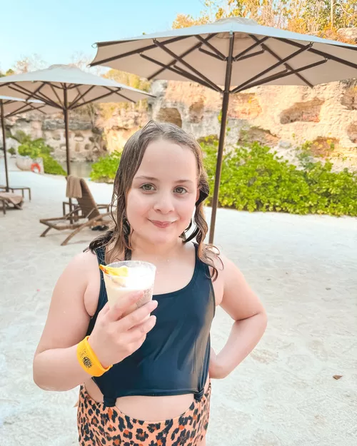 Little gilr drinks a virgin pina colada at Xcaret Hotel in Mexico
