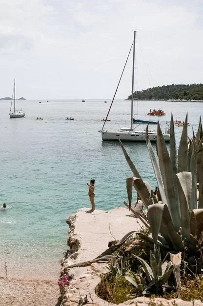 Person standing on a cliff near salboats on the water in Croatia.