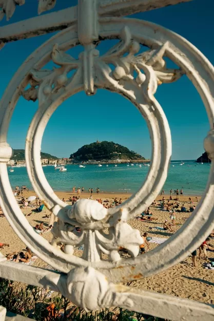 A view of a beach through a wrought iron fence in San Sebastian, Spain