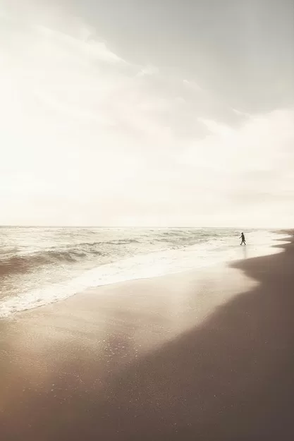 Person in the distance walking on the beach on a cloudy day