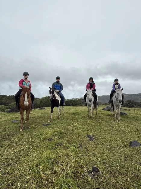 Mother, father, and two daughters looking at the camera while on horseback in Costa Rica