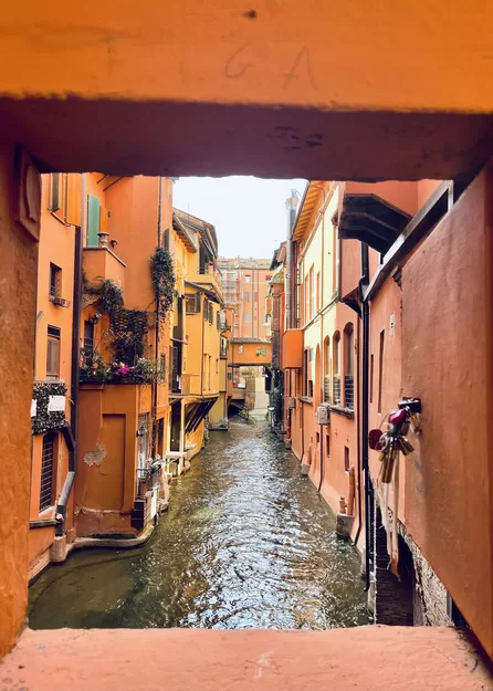 View from an orange stone window into a river in Bologna, a perfect stop on your trip to Italy