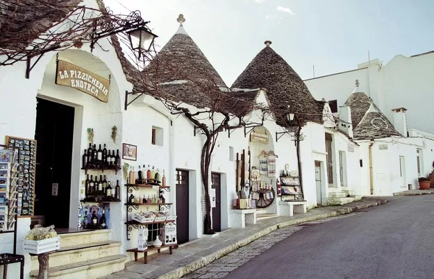 Bottle display outside stone building with thatched roof in Alberobello, Italy in Puglia, a great stop on your trip to Italy