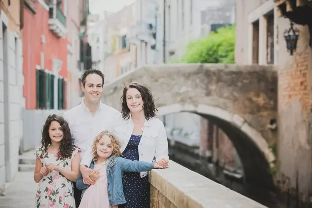 Mother, father, and two daughters posing for a Flytographer photo shoot in Venice. Beautiful pastel Venice is the perfect stop on a trip to Italy.