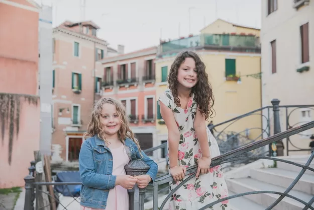 Two little girls posing for a Flytographer photo shoot in Venice. Beautiful pastel Venice is the perfect stop on a trip to Italy.
