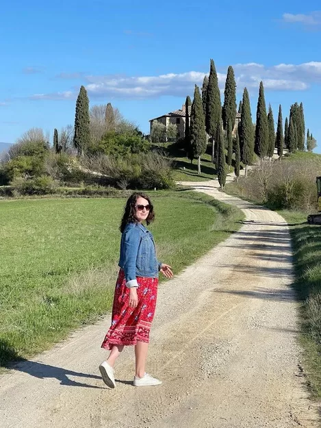 Woman walking on cypress lined road in Tuscany