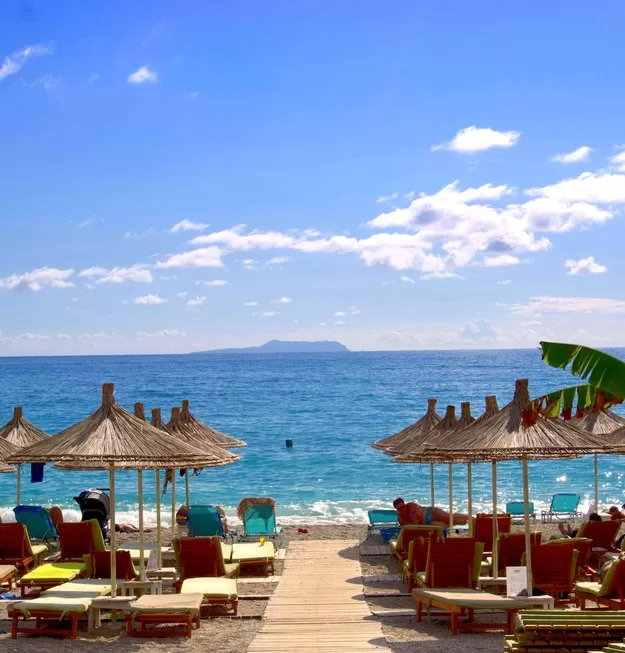 Albania is oen of the hottest destinations for a family trip to Europe - beach loungers with umbrellas near the ocean