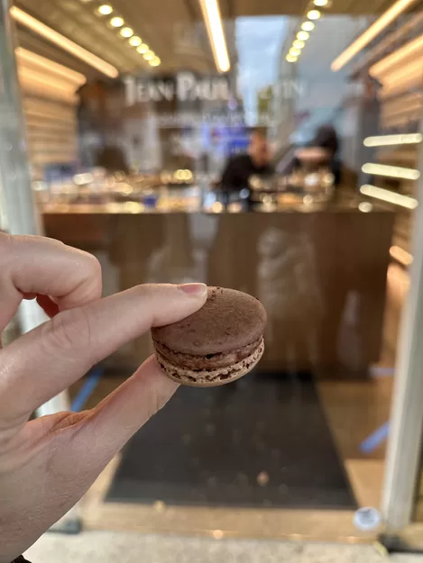 Hand holding a chocolate macaron in a Paris patisserie visited on a culinary tour of Paris