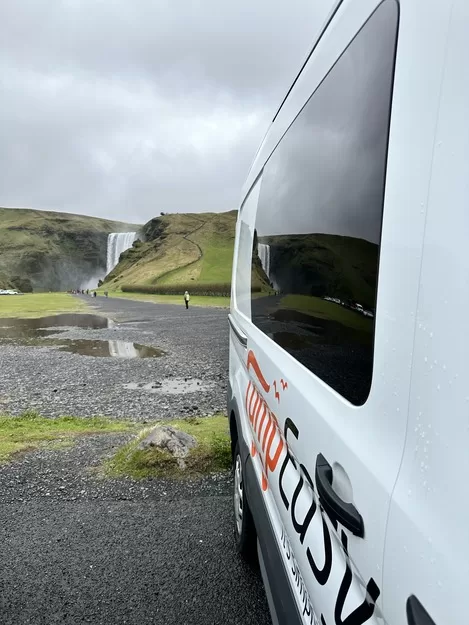 One of the best ways to get around Iceland with kids is a campervan. Here it's parked in front of a waterfall.